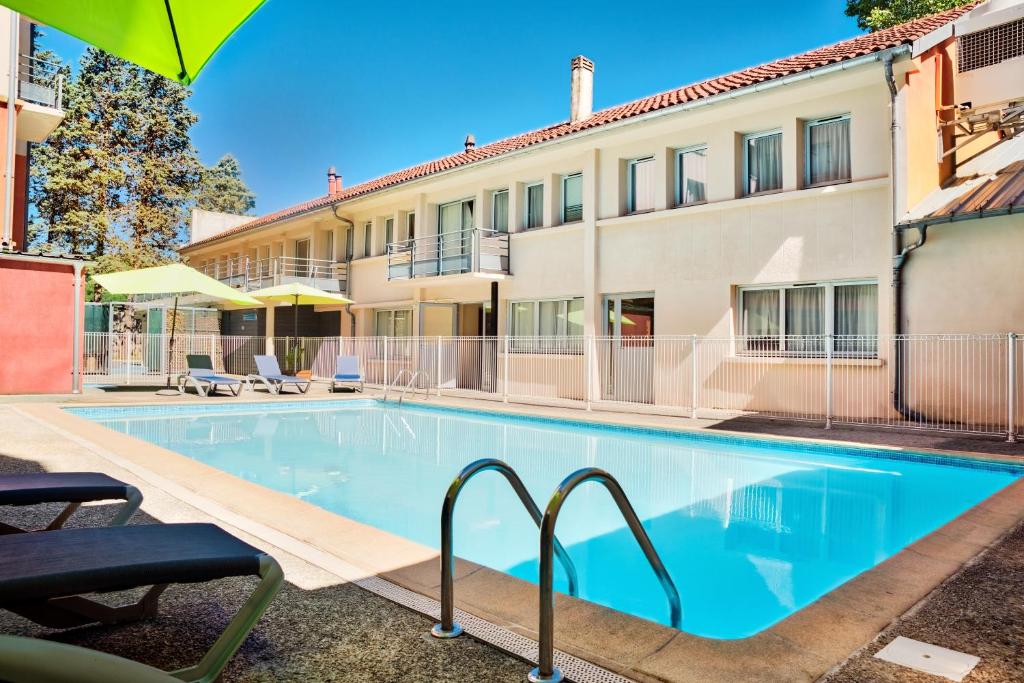 uma piscina em frente a um edifício em Zenitude Hôtel-Résidences Les Jardins de Lourdes em Lourdes