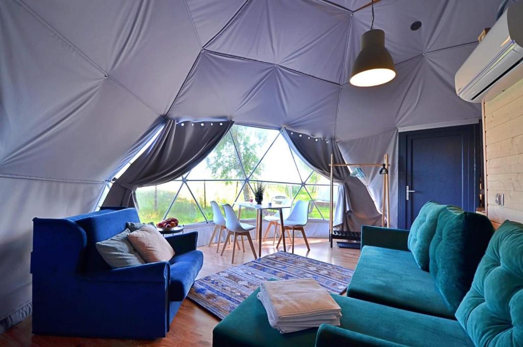 a living room with blue couches and a tent at Slowly Glamping Osada Nad Wodą in Łazy