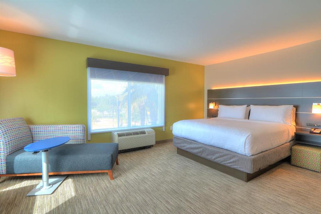 a large hotel room with a bed and a window at Holiday Inn Express Hotel & Suites Mobile Saraland by IHG in Saraland