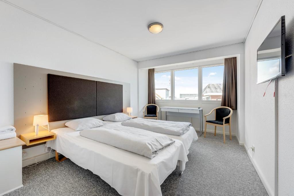 1 Schlafzimmer mit 2 Betten, einem Schreibtisch und einem Fenster in der Unterkunft Hvide Sande Hotel in Hvide Sande