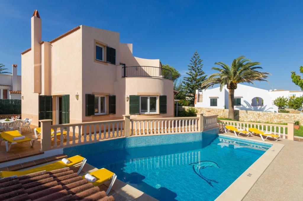 a villa with a swimming pool in front of a house at Villa Blancala 502 in Cala Santandria