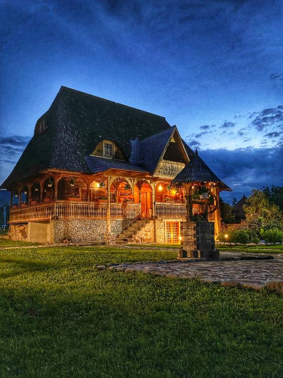 a large wooden house with lights on it at night at Casa Chira in Vişeu de Sus