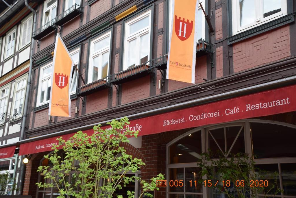 ein Gebäude mit orangefarbenen Flaggen auf der Vorderseite in der Unterkunft Café Burgstraße in Wernigerode