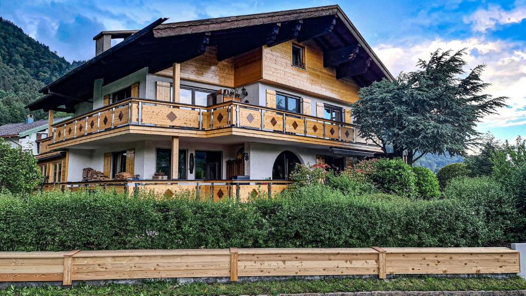 ein großes Holzhaus mit einem Zaun davor in der Unterkunft Urlaub beim Filmemacher Thomas Junker in Ruhpolding