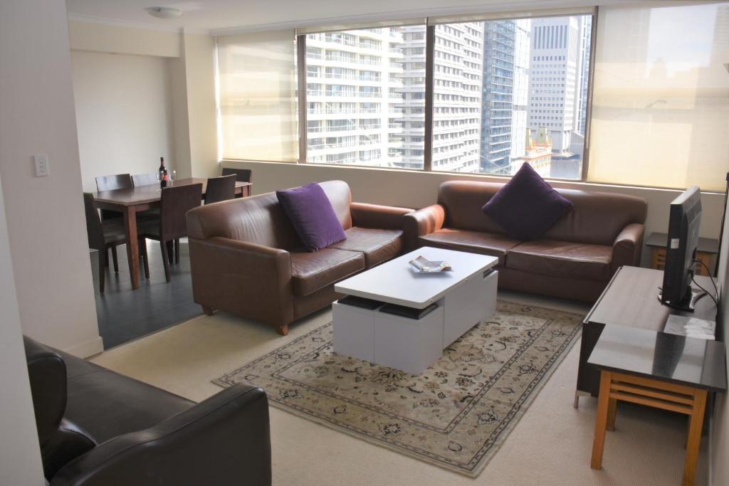 Accommodation Sydney - Hyde Park Plaza في سيدني: غرفة معيشة بها كنبتين وطاولة وطاولة