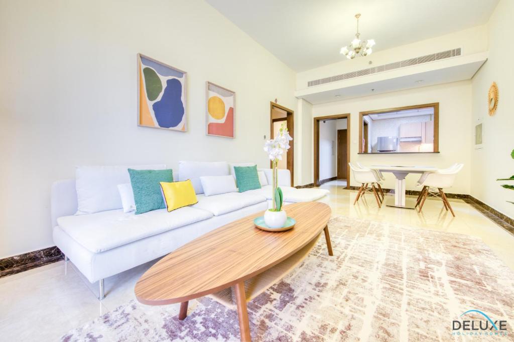 a living room with a white couch and a table at Vibrant 1BR at Pantheon Boulevard Jumeirah Village Circle by Deluxe Holiday Homes in Dubai