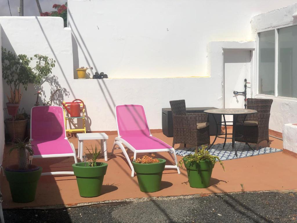 un patio con sillas rosas, una mesa y macetas en Casa La Mareta, en Casillas del Ángel