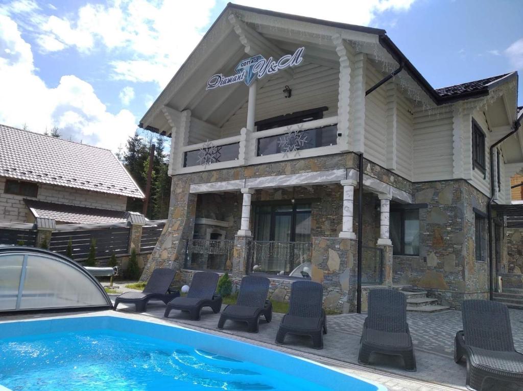 a house with chairs and a swimming pool in front of it at Cottage Diamant Y&M in Palyanytsya