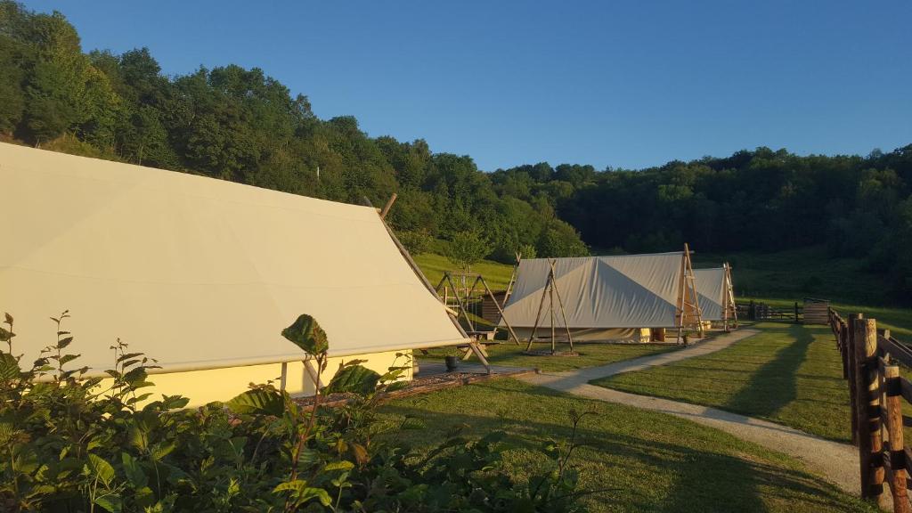 a group of tents in a field with trees at La P'tite ferme de la Vie in Survie