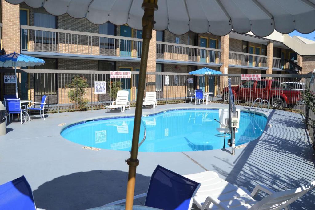 einem Pool mit Sonnenschirm vor einem Hotel in der Unterkunft Days Inn by Wyndham Easley West Of Greenville/Clemson Area in Easley