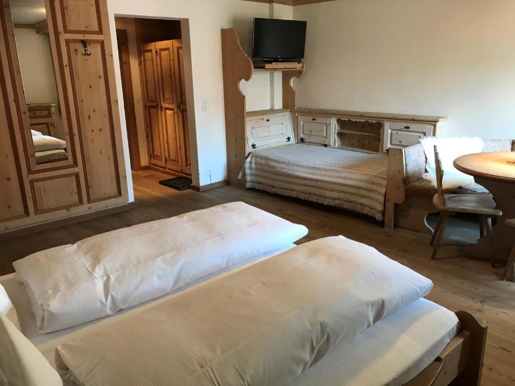 a bedroom with two beds and a tv on the wall at Hotel Klarer in Zuoz