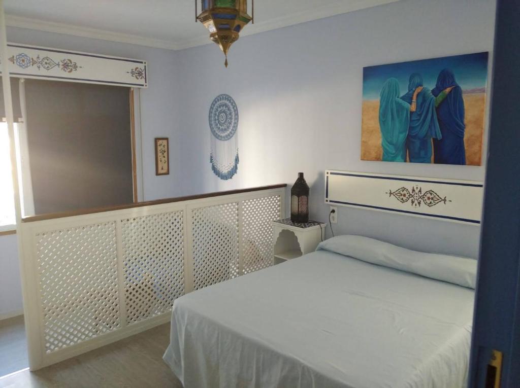 サンルーカル・デ・バラメダにあるEl apartaitoの白いベッドと壁に絵画が飾られたベッドルーム1室