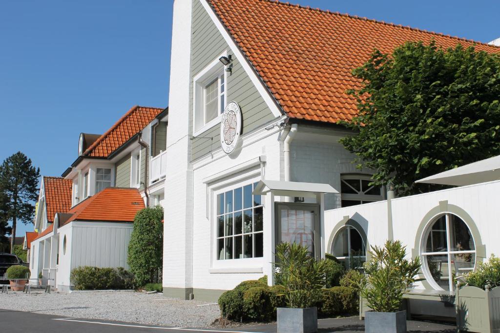 un bâtiment blanc avec une horloge sur son côté dans l'établissement Marie Siska Boutique hotel, à Knokke-Heist