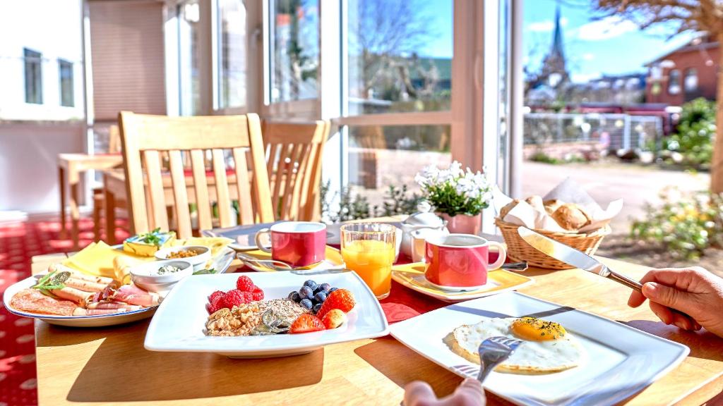 a wooden table with plates of breakfast food on it at Biohotel Amadeus in Schwerin