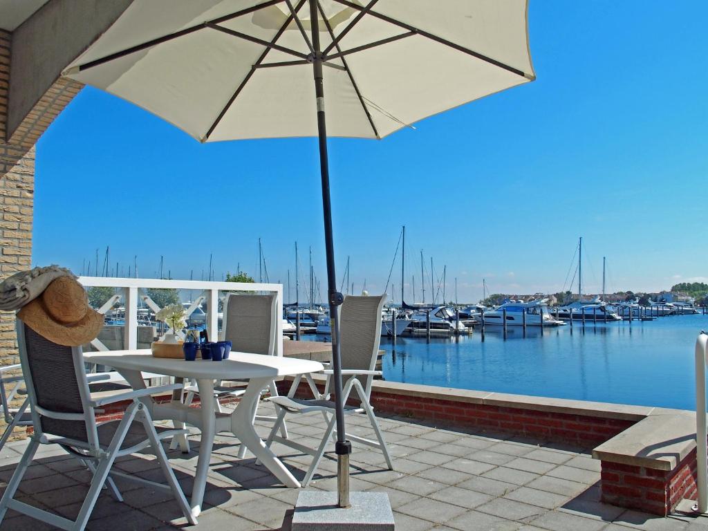 een patio met een tafel en stoelen en een parasol bij Vakantieappartement de Kabbelaar in Ouddorp