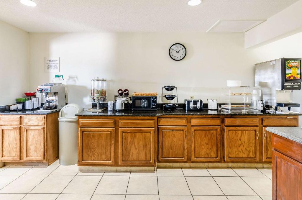 a kitchen with wooden cabinets and a clock on the wall at Econo Lodge Glade Springs I-81 in Glade Spring