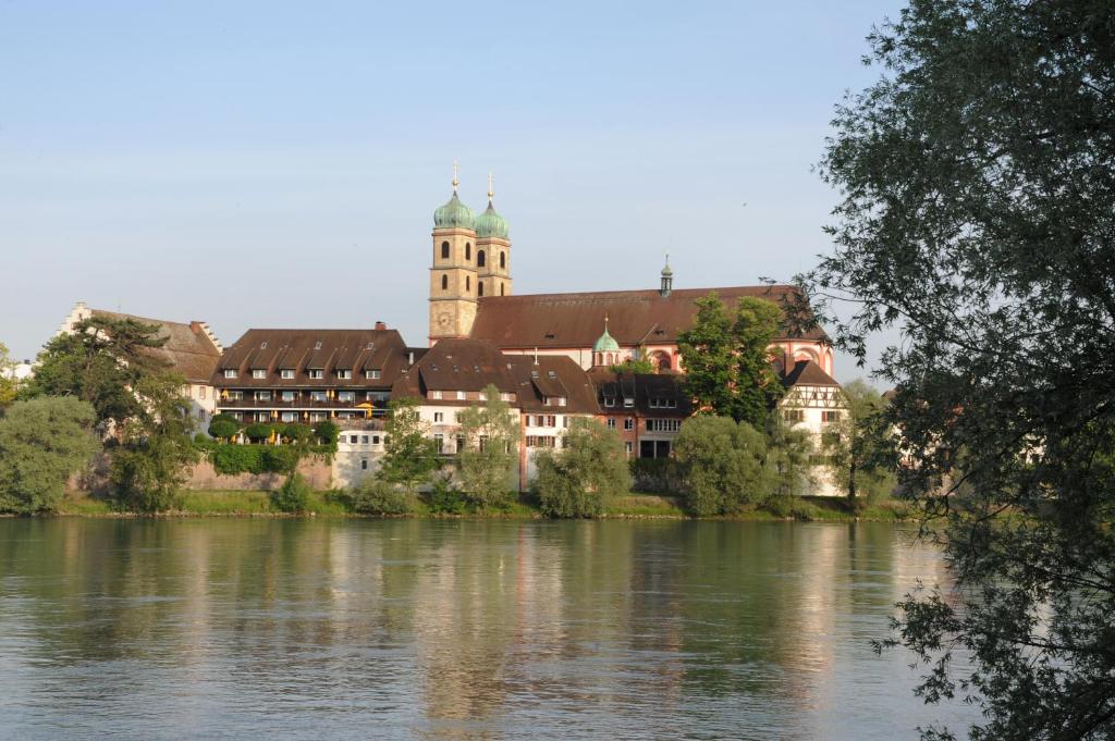 un edificio con torre dell'orologio accanto a un fiume di Hotel Goldener Knopf a Bad Säckingen