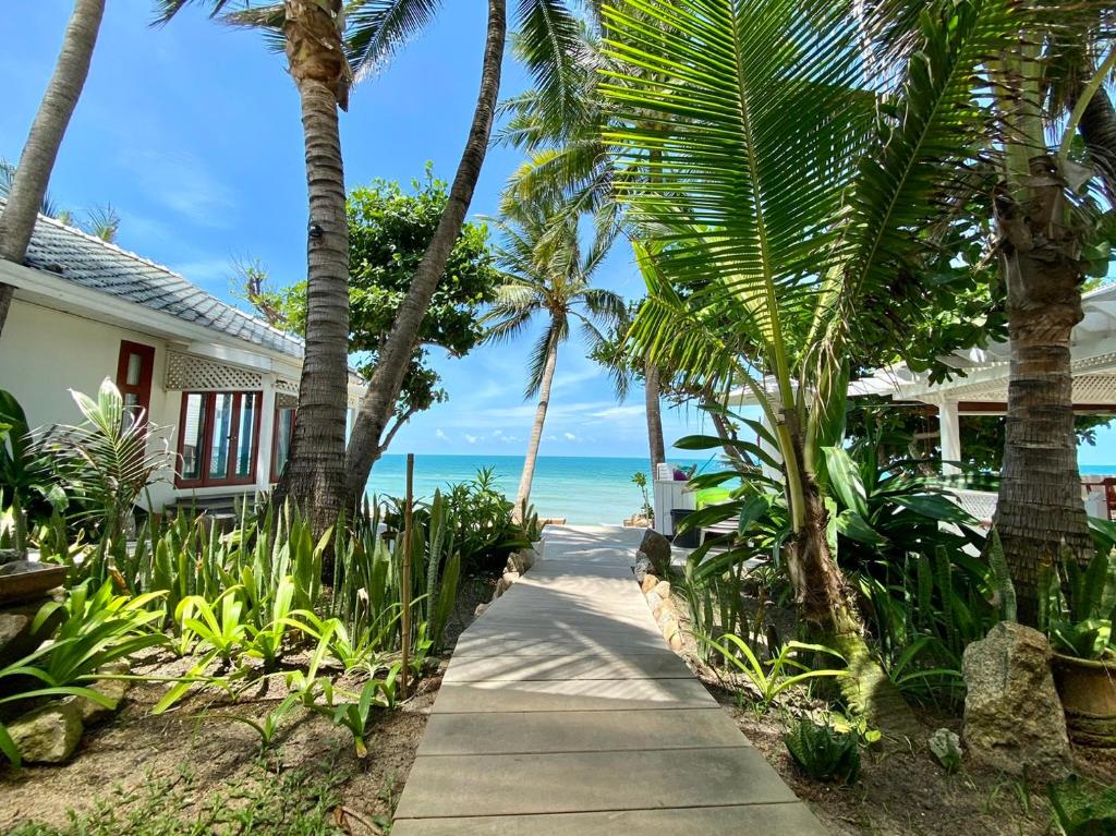 a path to the beach with palm trees and a house at Sans Souci Samui - SHA Plus in Chaweng