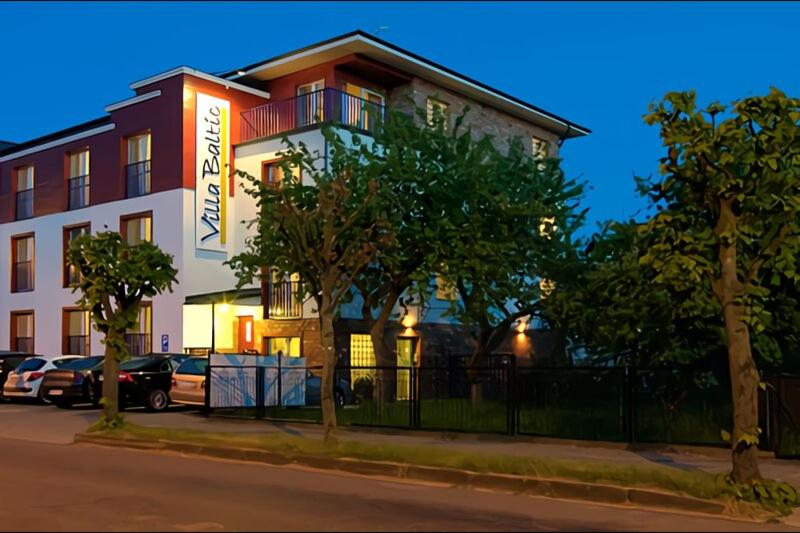 duży budynek z samochodami zaparkowanymi przed nim w obiekcie Villa Baltic Chałupy - Apartament nr 1 w Chałupach
