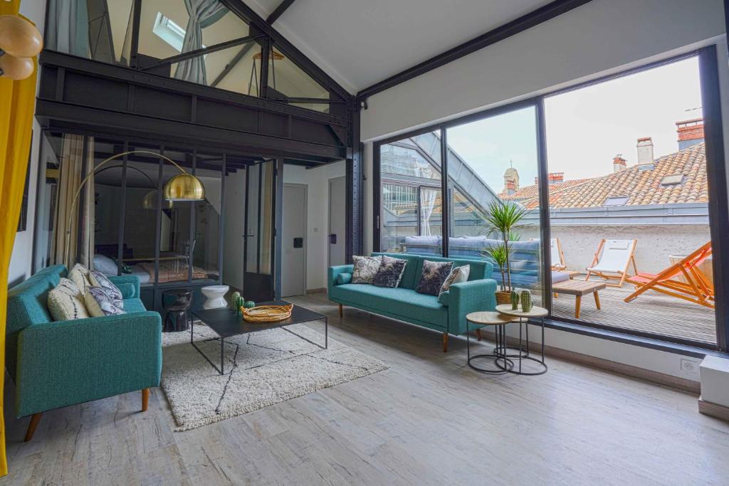 ein Wohnzimmer mit blauen Möbeln und großen Fenstern in der Unterkunft NOCNOC - Le Loft, terrasse comédie in Montpellier