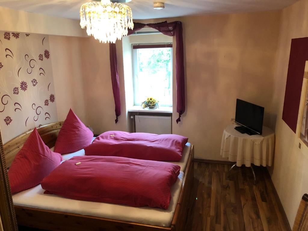 een kamer met roze kussens op een bed met een raam bij Deutsches Haus in Neuhütte