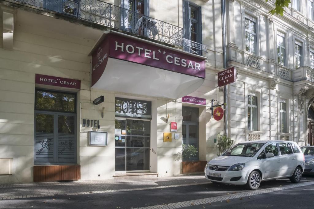 un coche aparcado frente a un hotel cregem en Citotel Hôtel Cesar, en Nimes