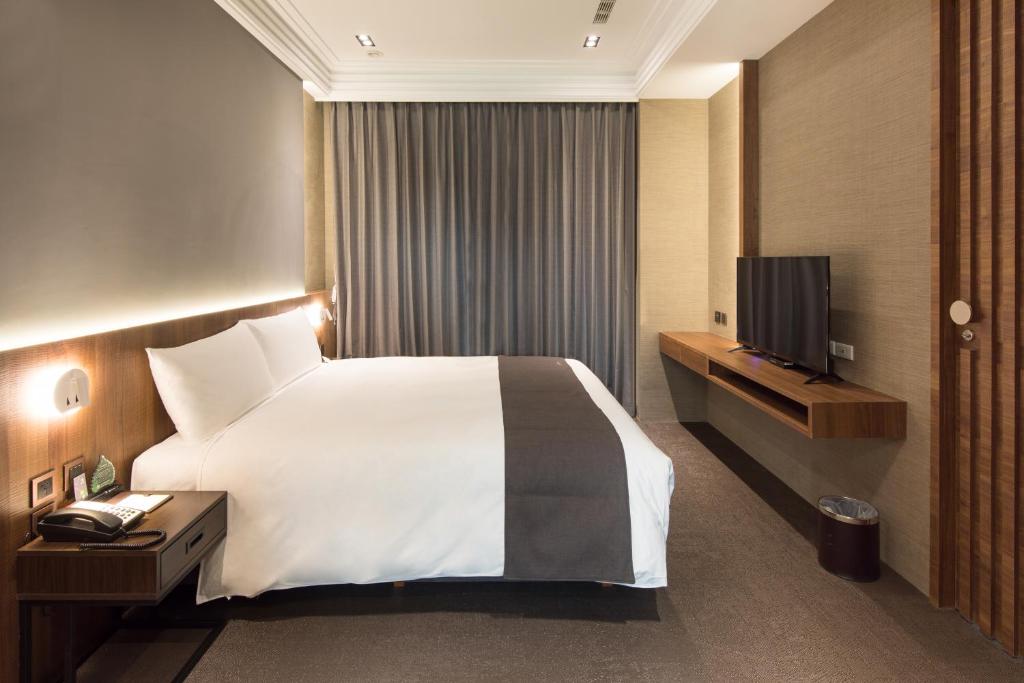 une chambre d'hôtel avec un lit et une télévision dans l'établissement He-Jia Hotel, à Miaoli