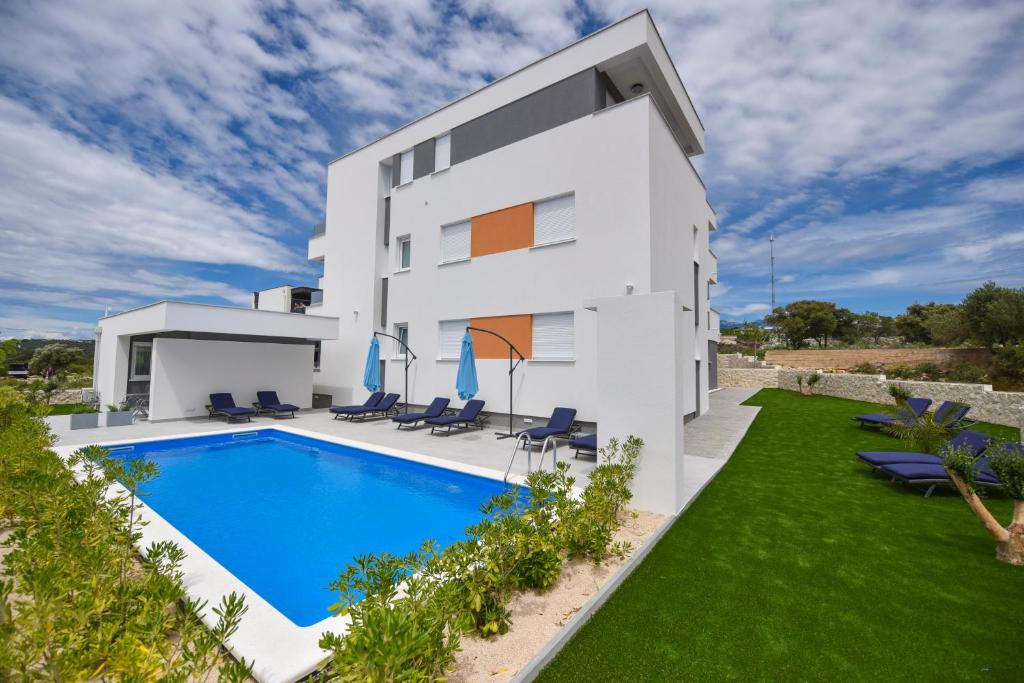 a white house with a swimming pool and lawn at Pool Apartments & Rooms Mare in Novalja