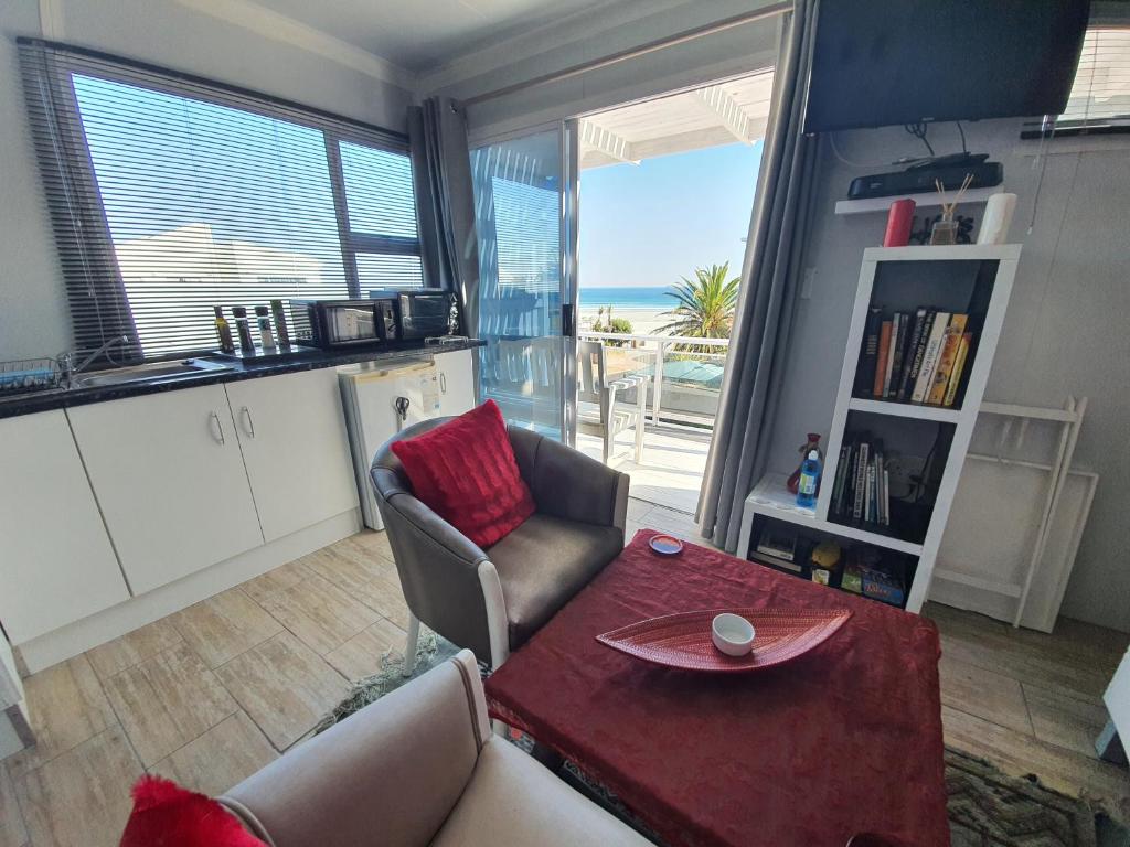 Sala de estar con mesa y vistas al océano en Atlantic Studio - Compact unit with Sea Views, en Melkbosstrand