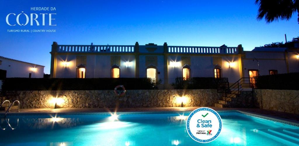 a large house with a swimming pool at night at Herdade Da Corte in Tavira