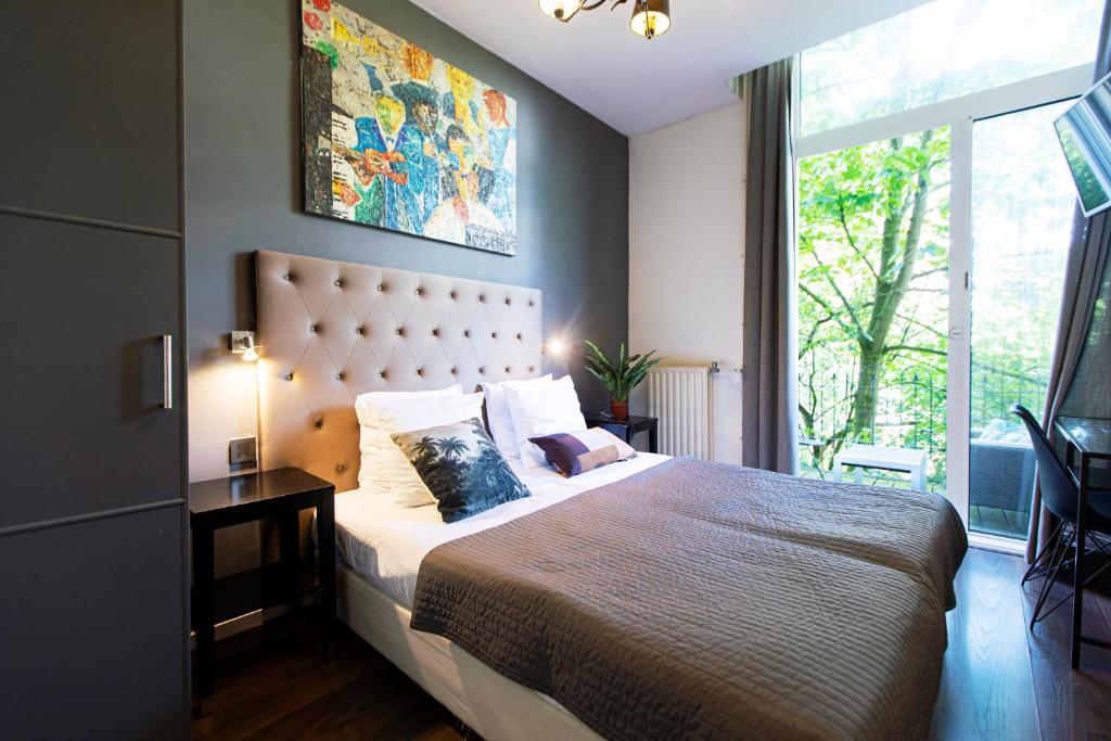 um quarto com uma cama grande e uma janela grande em Quentin England Hotel em Amsterdã