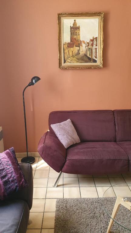a purple couch in a living room with a painting at Close to centre, 3 rooms, 2 bathr & wc, free parking & wifi, spacious living area & kitchen in Bruges