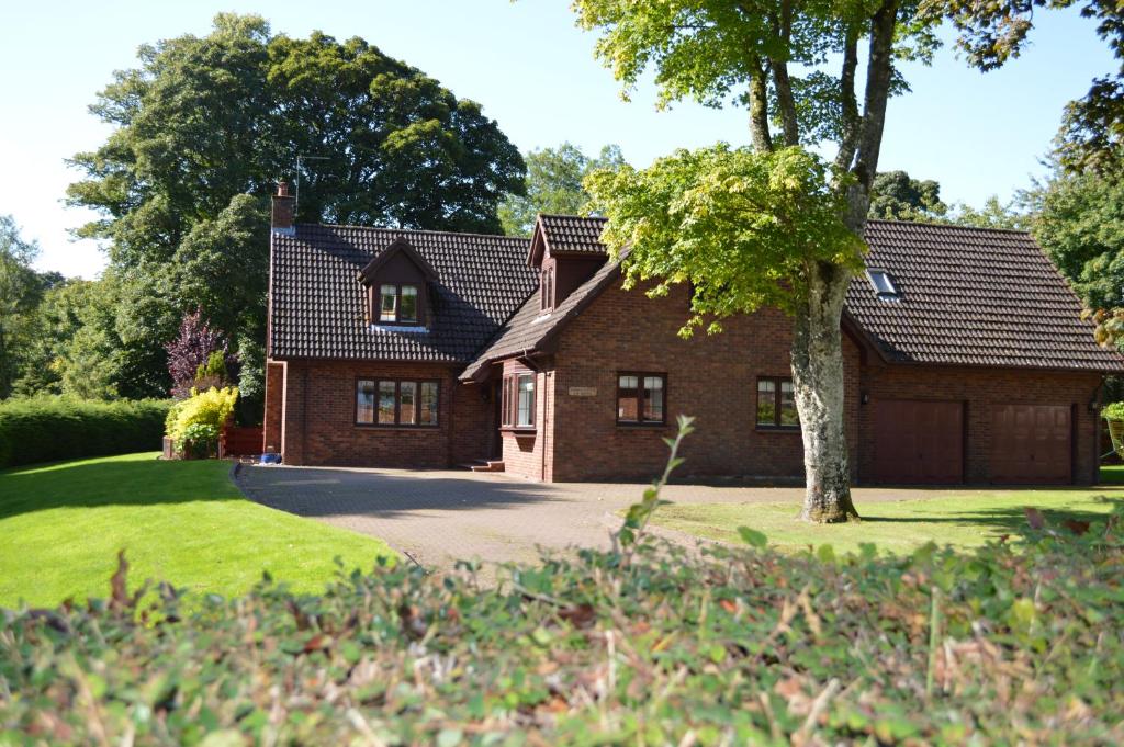 ein Backsteinhaus mit einem Baum davor in der Unterkunft Auburn Cottage in Arbroath