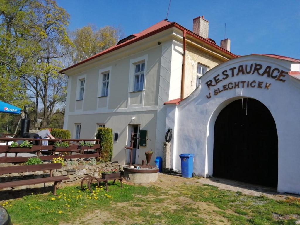 a white building with a garage and a sign on it at Penzion U Šlechtičen in Milovy