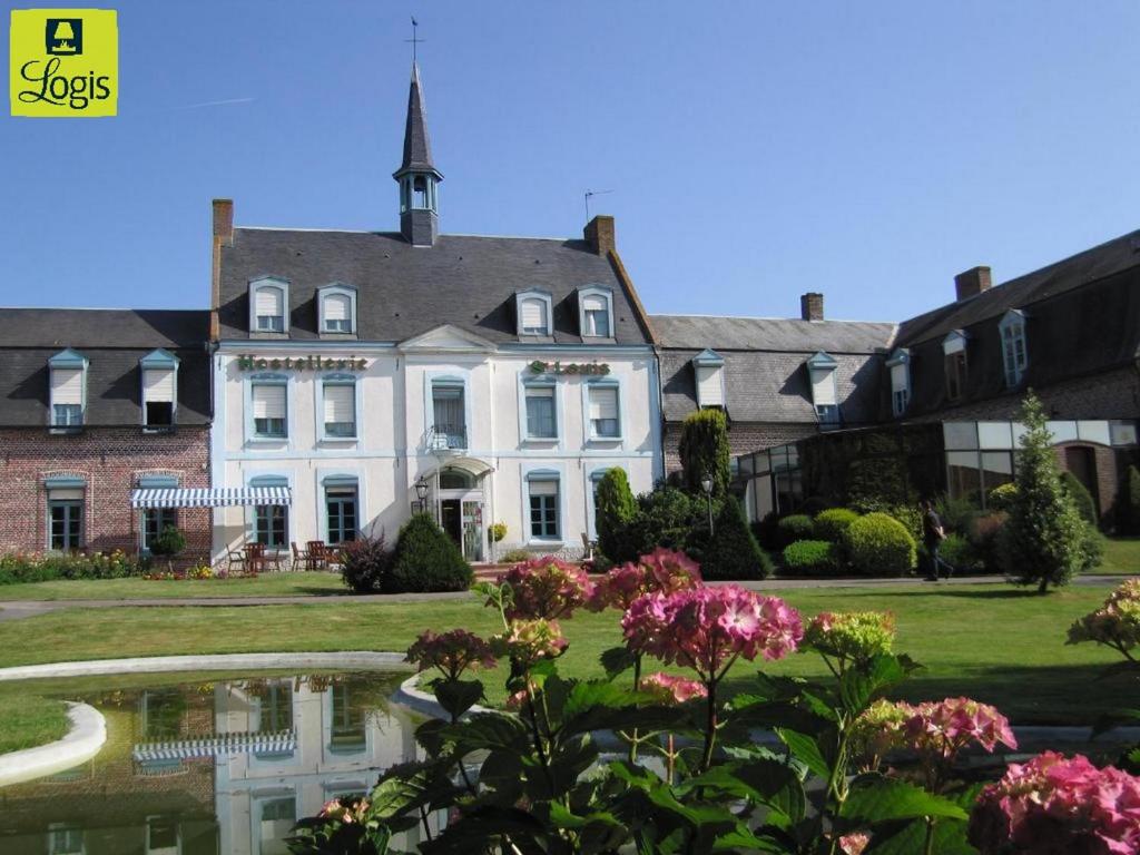 a large white house with a pond in front of it at Logis - Hostellerie & Restaurant Saint Louis in Bollezeele