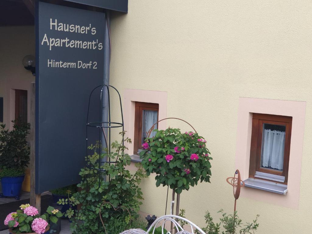 a sign on the side of a building with flowers at Hausner`s Hotel-Apartments in Altenstadt an der Waldnaab