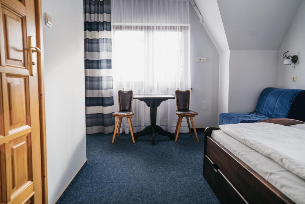 布科維納塔特贊斯卡的住宿－Hawrań Bukowina，一间卧室配有一张床、一张桌子和两把椅子