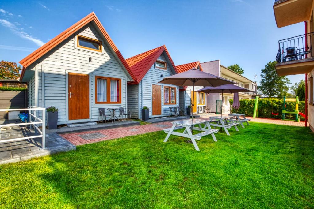 a house with a yard with tables and an umbrella at Domki Olivia in Władysławowo