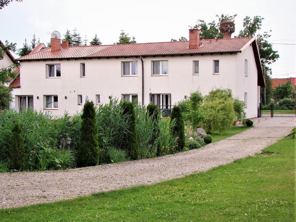 une grande maison blanche avec une allée en gravier dans l'établissement Pokoje Przy Kominie, à Piecki