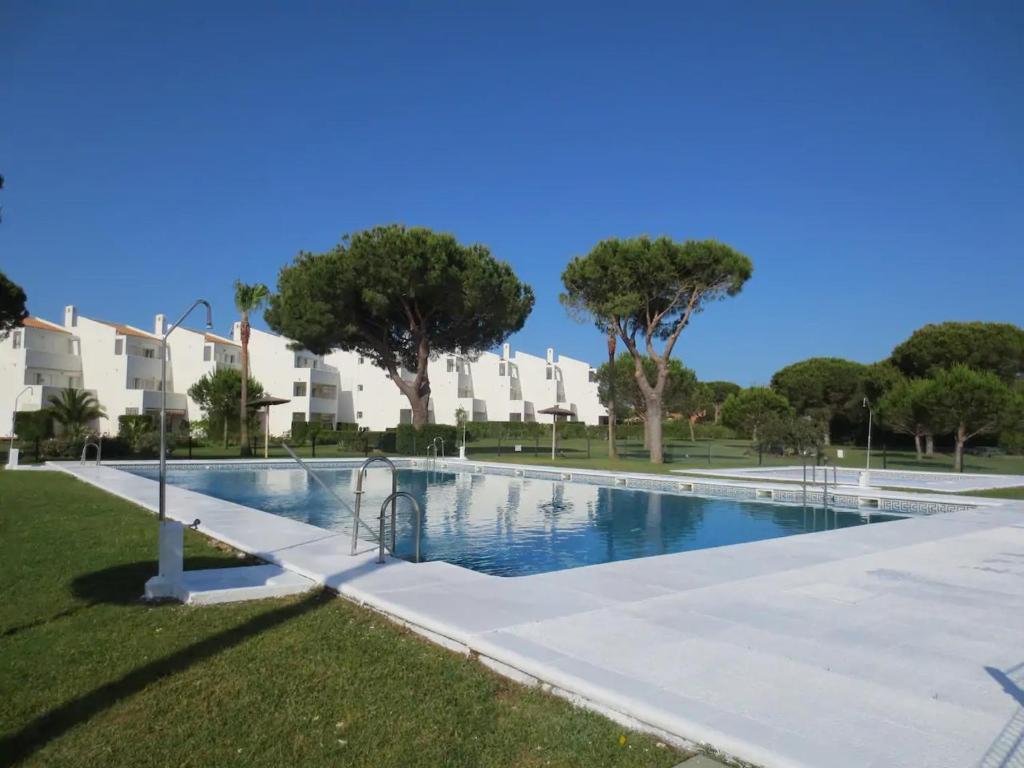 a swimming pool in a park with trees and buildings at Novo Sancti Petri - Playa, Piscina, Golf y Relax in Chiclana de la Frontera
