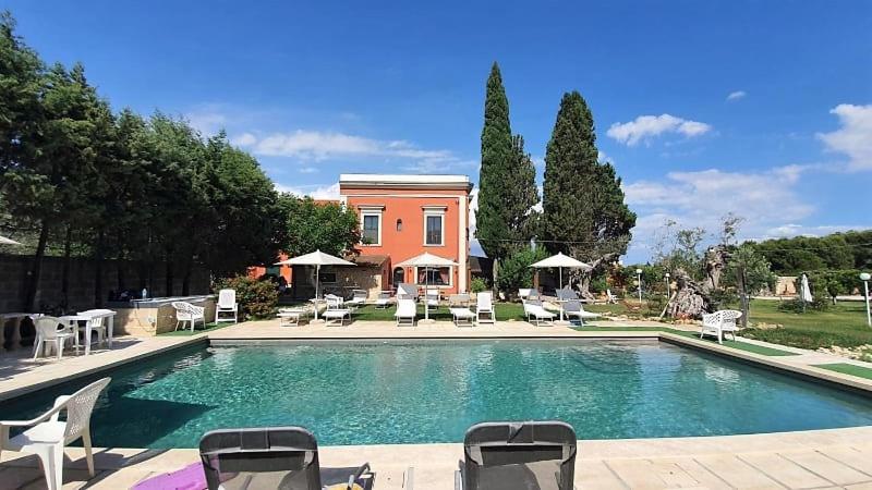 a swimming pool with chairs and a house in the background at Agriturismo Santa Chiara in Alezio