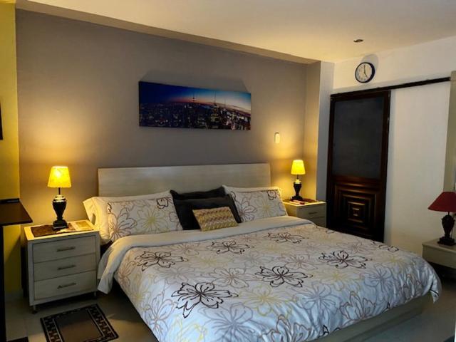 1 dormitorio con 1 cama, 2 lámparas y reloj en Apartaestudio El Lugar Ideal Cra. 62 #74-143., en Barranquilla