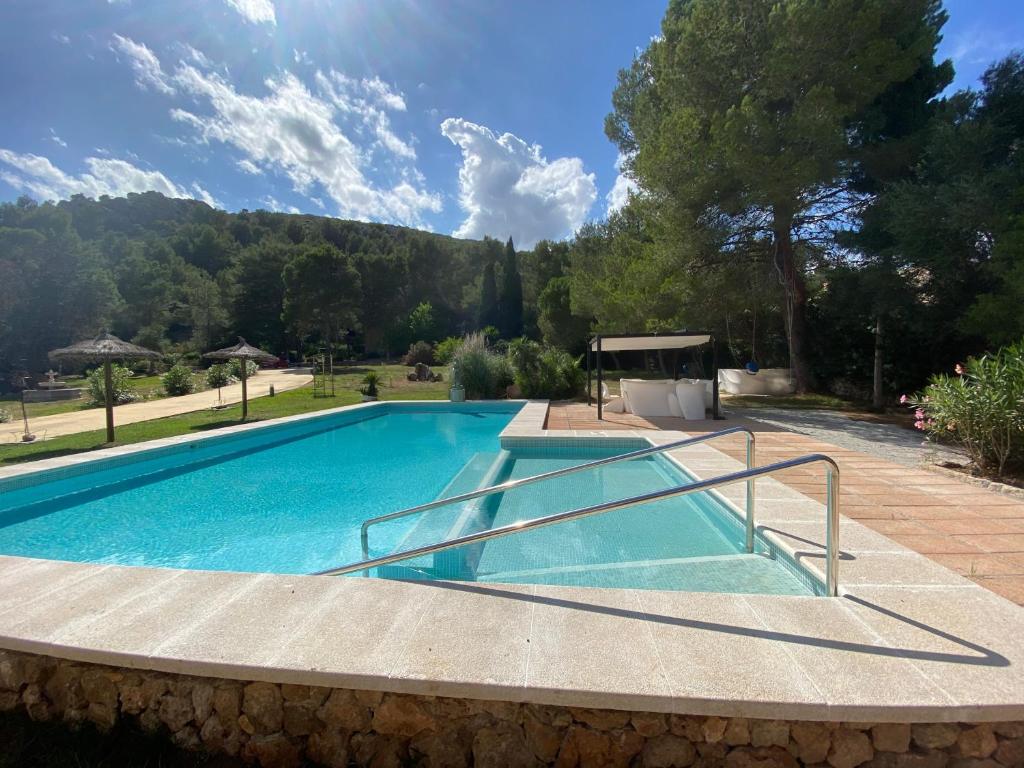 einen Pool in einem Garten mit Bäumen und einem Himmel in der Unterkunft Private Villas Puerto Pollensa in Port de Pollença