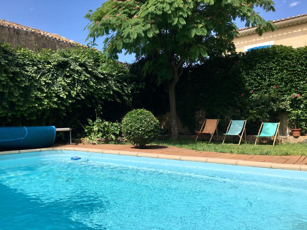 a swimming pool with two chairs and a tree at La Casa Deva - Maison d Artistes in Montredon