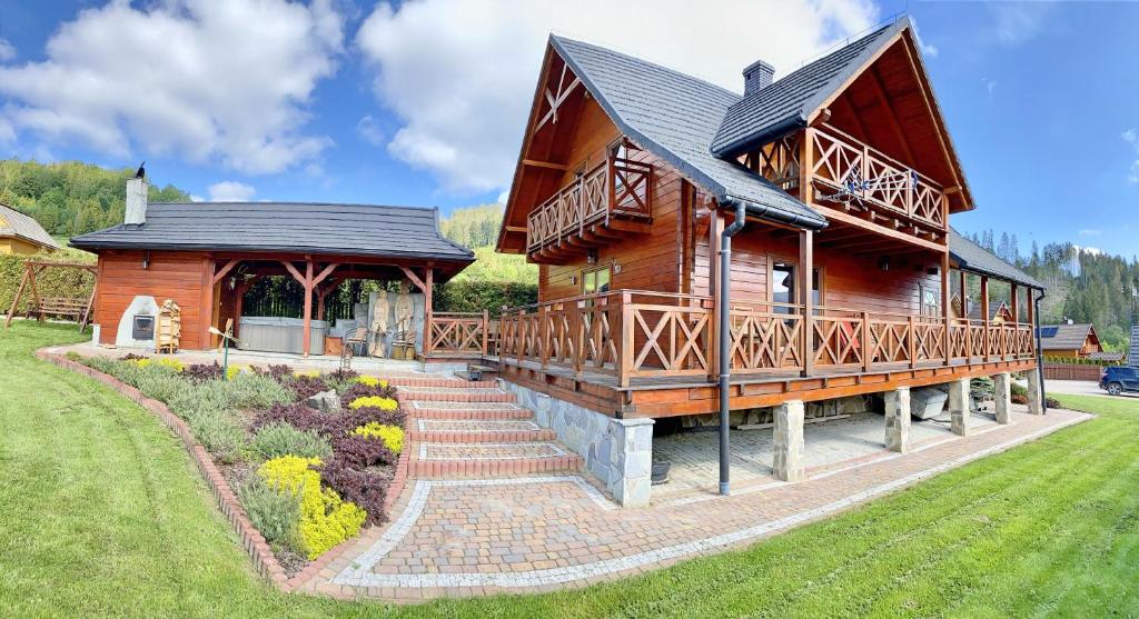 ein großes Holzhaus mit einer Veranda und einer Treppe dorthin in der Unterkunft Cichy Zakątek in Ujsoły