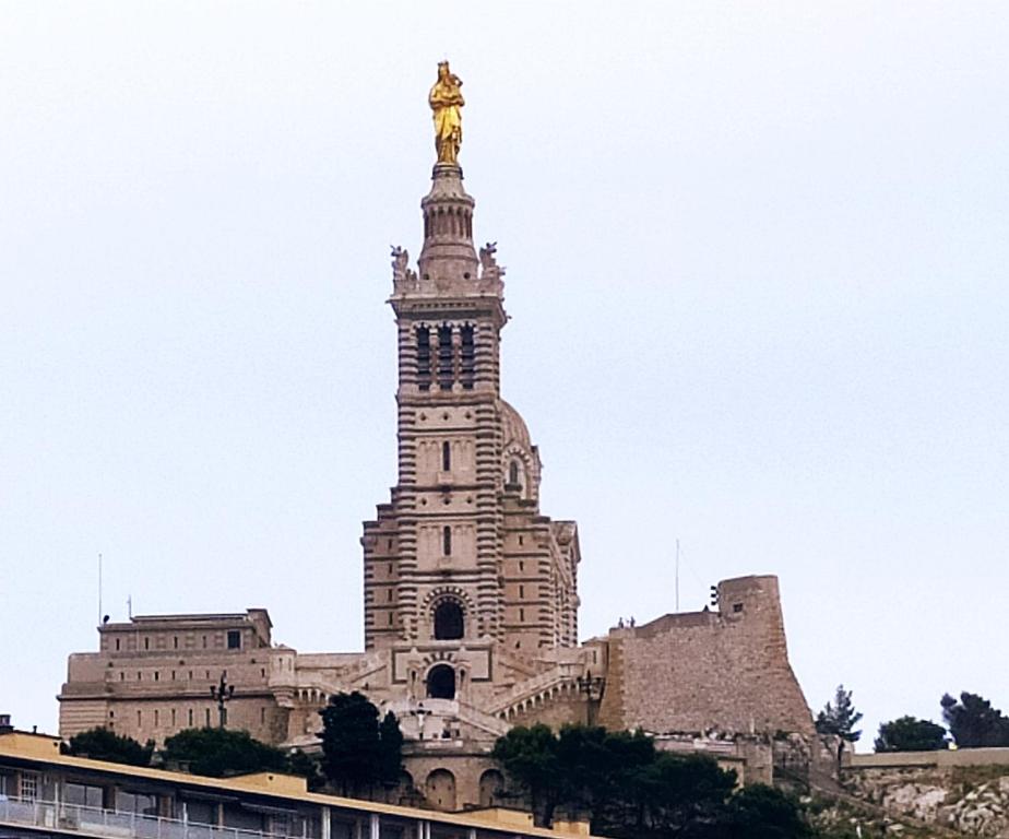 マルセイユにあるT2 Vue sur la Basilique de Notre Dame de la Gardeの像が立つ高層ビル
