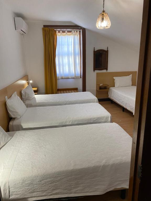 una camera d'albergo con due letti e una finestra di Guesthouse Lusa Atenas a Coimbra