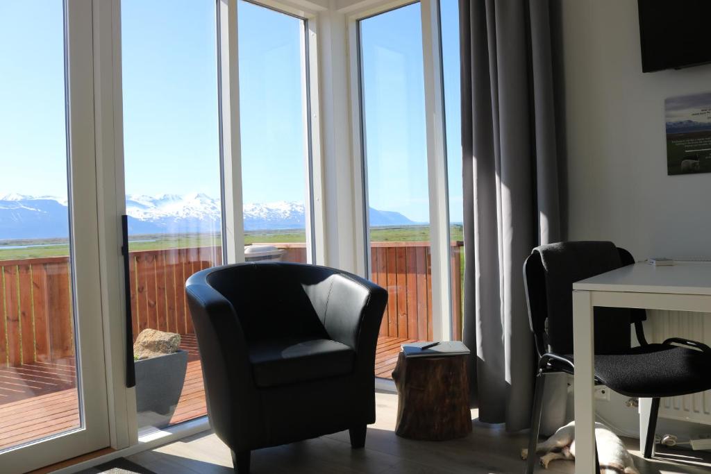 um quarto com duas cadeiras, uma mesa e janelas em Laxhús em Húsavík