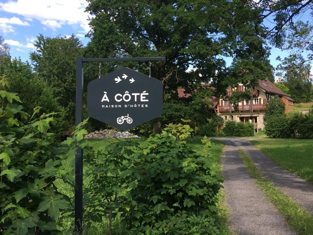 un panneau de cottage en face d'une allée. dans l'établissement A Côté, à Oron-la-ville