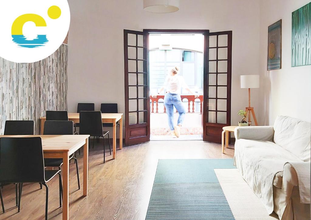 a living room with a table and a woman walking out the door at Casa Canaria Beautiful Home in Las Canteras in Las Palmas de Gran Canaria